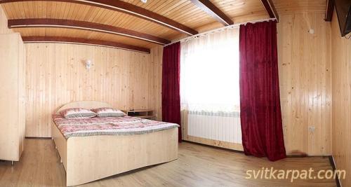 a bedroom with a bed and a large window at Сонячний in Slavske