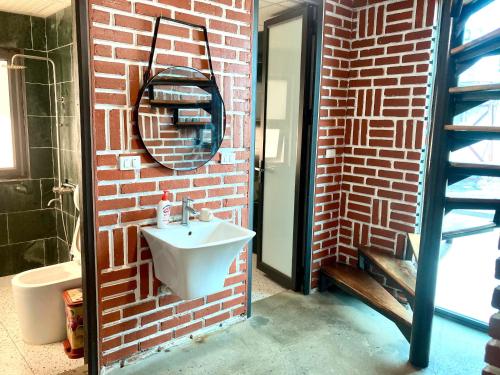 a bathroom with a sink and a brick wall at Greenfield Ba Vì - Nắng Villa in Yên Bài