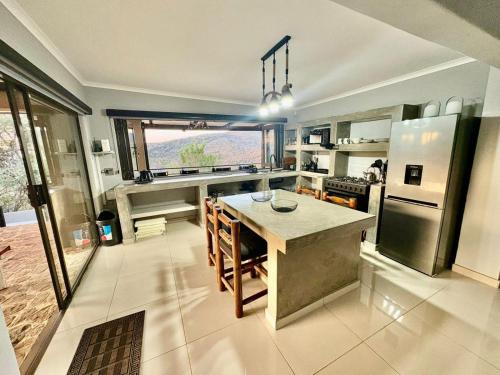 a large kitchen with a table and a large window at Athule Inn - Cradle in Hekpoort
