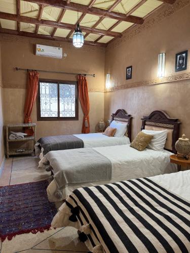 a bedroom with three beds in a room at Berber Nomad Kasbah in Nkob
