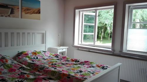 a bedroom with a bed with a floral bedspread and two windows at Birkenhof in Achtrup