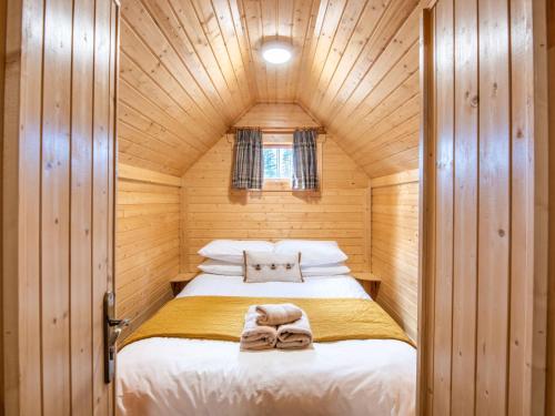 a small bedroom with a bed in a wooden cabin at Chalet Oak Bothy by Interhome in Coldstone