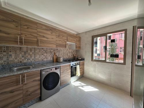 a kitchen with wooden cabinets and a dishwasher at Le Balcon Bohème des Golfs in Marrakesh