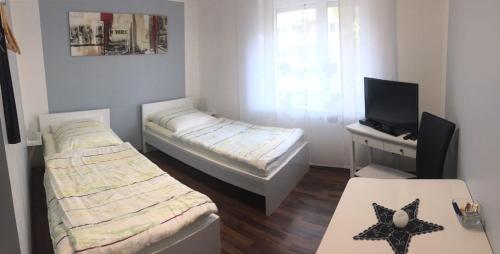 a small room with two beds and a television at Ferien - und Messewohnung am Wöhrder See in Nürnberg