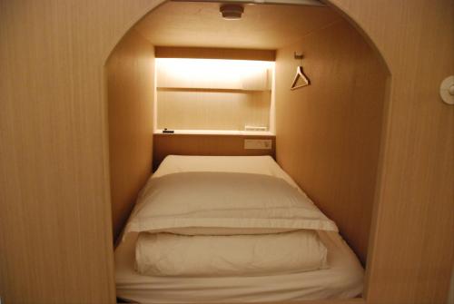 a small bedroom with a bed in a small room at 굿데이 큐브 캡슐 호텔 in Busan