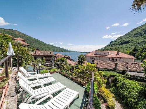 a group of white chairs sitting on a patio overlooking the water at Apartment Piersa by Interhome in Mergozzo