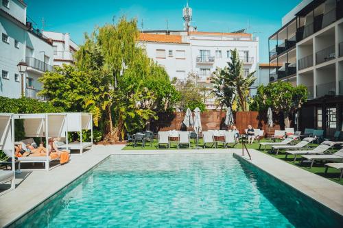a swimming pool in a hotel with tables and chairs at Hotel Windsor Tossa - Adults Only 16 in Tossa de Mar