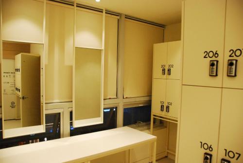 a room with white cabinets and a kitchen with a refrigerator at 굿데이 큐브 캡슐 호텔 in Busan