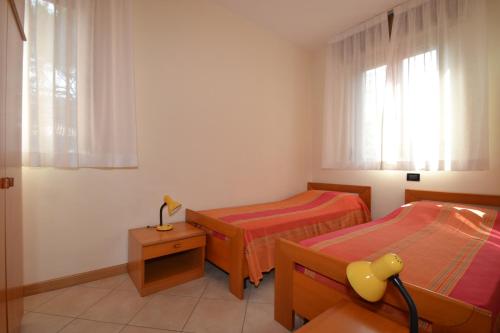 a bedroom with two beds and a table and a window at Orchidea in Bibione