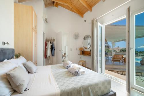 a white bedroom with a bed and a balcony at Villa Olivia Panoramic Sea View in Lefkada