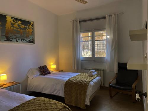 a bedroom with two beds and a chair and a window at Casa Belladona Barcelona in Barcelona