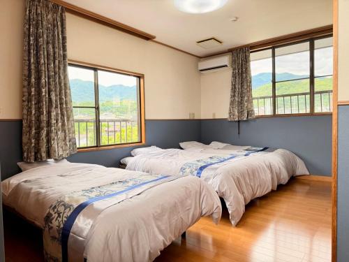 two beds in a room with two windows at 一棟貸し宿marusamarche in Fuefuki