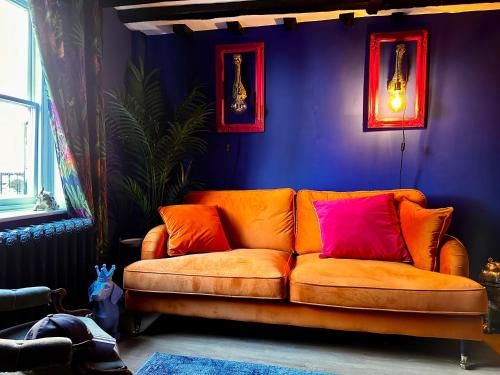 an orange couch in a room with a purple wall at Romantic Boutique Cottage with pink roll-top bath-Hastings Old Town in Hastings