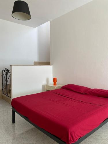 a bedroom with a red bed with a white wall at Orsa Maggiore apartment with private courtyard in Uggiano la Chiesa