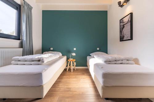 two beds in a room with blue walls and wooden floors at De Goudbalpeer - Ruim en luxe vakantiehuis voor 6 personen met uitzicht op wijngaard in Ruinerwold