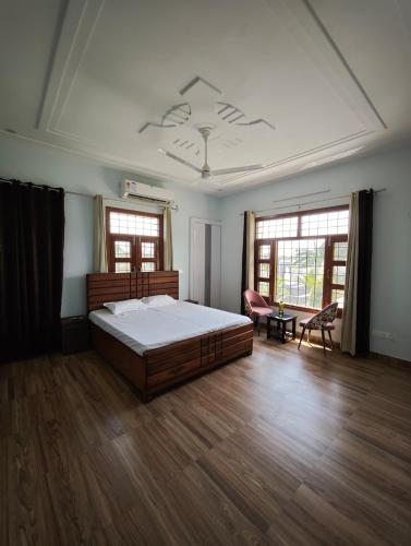 a bedroom with a bed and a table and two windows at Green Paradise 2BHK Villa with a Pool in Rishīkesh