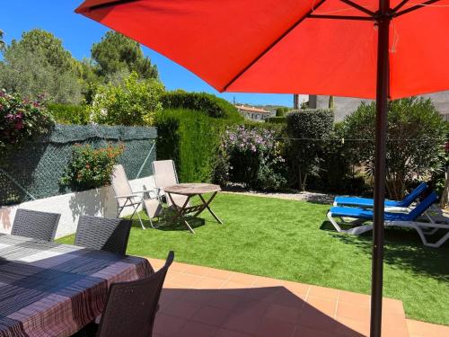 a patio with a table and a red umbrella at Breda 4a in Torroella de Montgrí