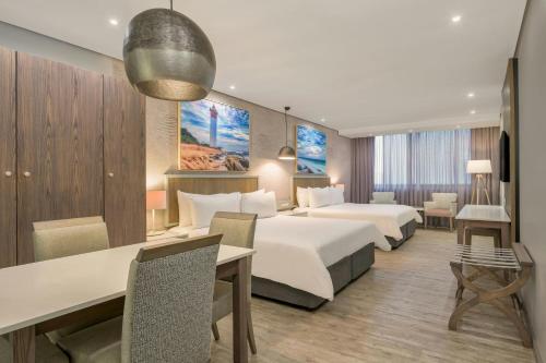 a hotel room with two beds and a desk at Protea Hotel by Marriott Durban Umhlanga in Durban