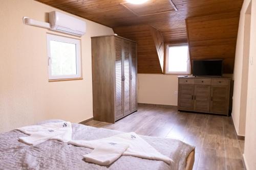 a bedroom with a bed and a cabinet and two windows at Tisza Apartman Mártély in Mártély