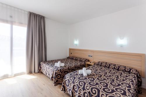 a hotel room with two beds and a window at Tossa Beach Center in Tossa de Mar