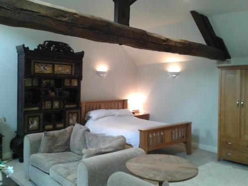 a bedroom with a bed and a couch and a table at The Gate House Barn in Stanton in Peak