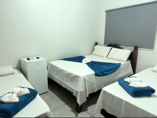 a room with three beds with towels on them at HOTEL TROPICAL in Jardim