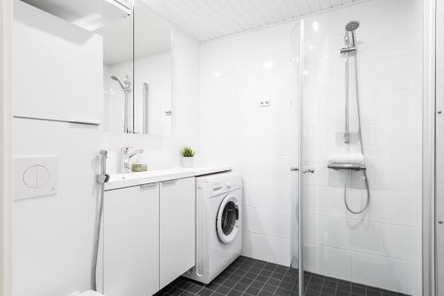a white bathroom with a washing machine and a shower at Hiisi Homes Turku Fleminginkatu in Turku