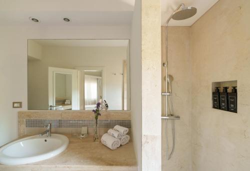 a bathroom with a tub and a sink and a mirror at The Village Chia Laguna Sardinia in Chia