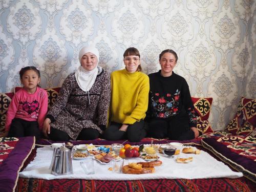 a group of people sitting around a table with food at Mamyr Guest House in Sary-Mogul