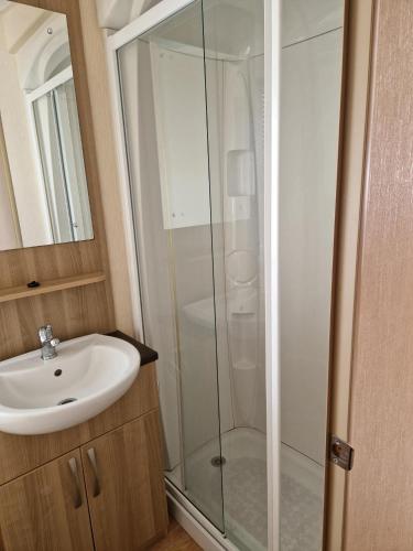 a bathroom with a glass shower and a sink at Sunblast- Dawlish Warren in Cockwood