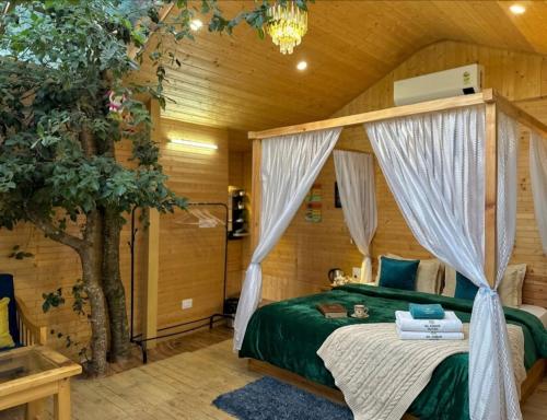 a bedroom with a canopy bed and a tree at UrWish TreeHouse cottageJacuzzi in Jibhi