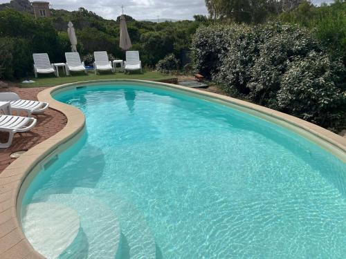 a large blue swimming pool with chairs and umbrellas at Sea Sky Villa with private pool in Costa Paradiso