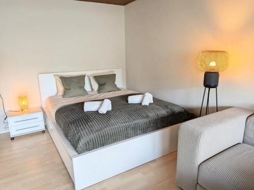 a white bedroom with a bed and a chair at Sunshine Suite in Ingenbohl