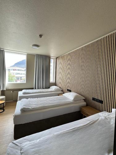 a bedroom with three beds and a window at Hotel Isafjördur - Torg in Ísafjörður