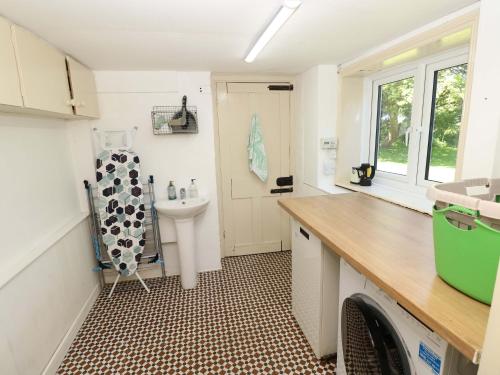 a small bathroom with a sink and a washing machine at Sweet Briars in Chalegreen