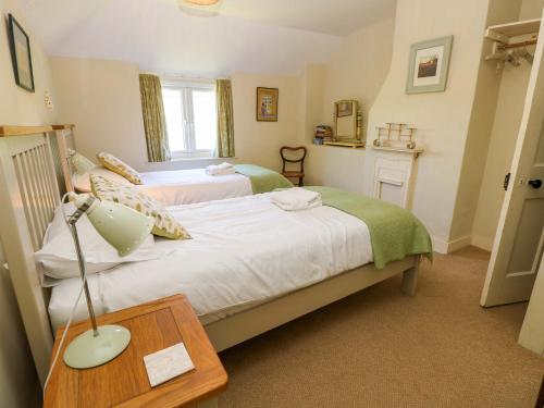 a bedroom with two beds and a lamp on a table at Sweet Briars in Chalegreen
