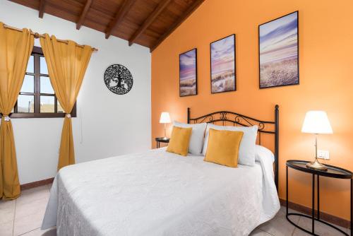 a bedroom with a white bed with orange walls at Home2Book Las Tinajas A, Peaceful Retreat in Triquivijate