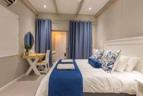 a bedroom with a bed and a table and a desk at 8 On Fleur Park Beach in Gordonʼs Bay