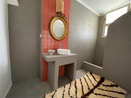 a bathroom with a sink and a mirror and a rug at Casa Pimenta in Vidigueira
