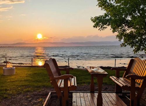 two chairs and a table with a sunset over the water at Chalet #2 Waterfront with Spa, Fireplace Wifi & AC in Cap-Saint-Ignace
