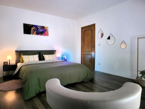 a bedroom with a large bed and a ottoman at Chez Toi Ailleurs - Dinant in Dinant