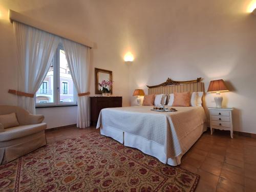 a bedroom with a bed and a chair and a window at Odisseo Apartments in Minori