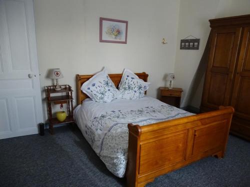 a bedroom with a wooden bed with pillows at Roses de Picardie in Chauny