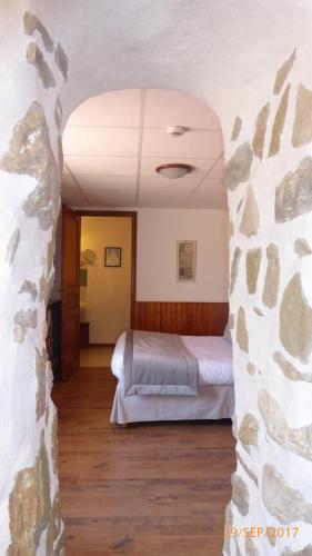 a bedroom with a bed and a stone wall at Auberge le Collet in Saint-Agnan-en-Vercors