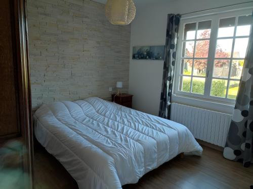 a bed in a bedroom with a brick wall at Gîte 10 Couchages À Barfleur in Barfleur