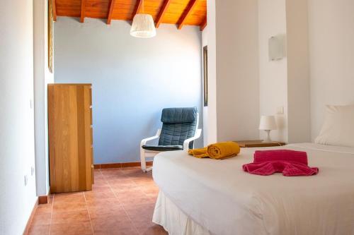 a bedroom with a bed and a blue chair at Casa Be in Caleta De Fuste