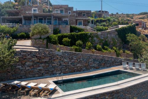 a villa with a swimming pool and a stone wall at Kea Village Suites & Villas in Ioulis