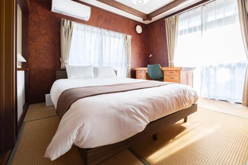 a bedroom with a large bed and a window at 湯のん - Yunon - 温泉付き一棟貸し古民家 指宿名物 砂むし温泉徒歩2分 最大11名 in Ibusuki