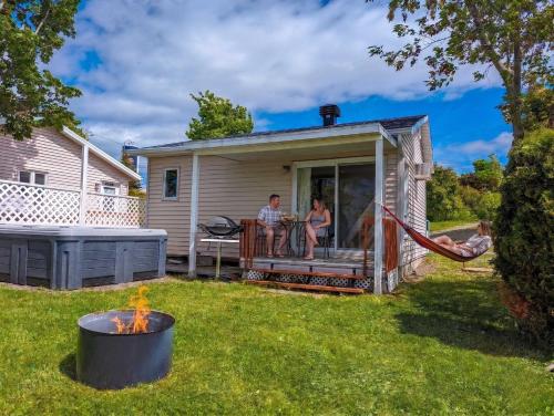 a man and woman sitting on the porch of a house at Chalet Studio #3 Waterfront with Spa, Fireplace & Wifi in Cap-Saint-Ignace