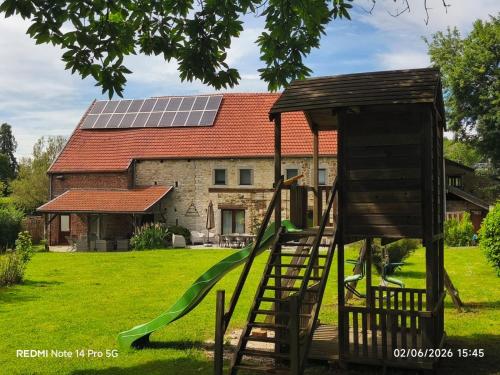 a playground in front of a house with a solar roof at Le gîte d’Hayen in Sprimont